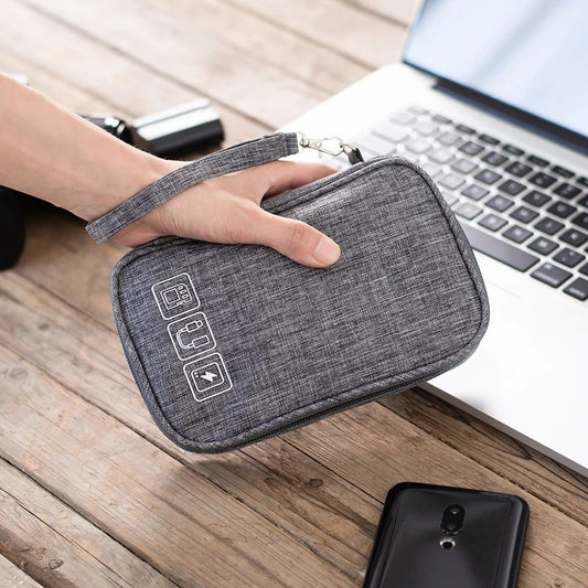 Gray travel organizer held by a hand on a wooden surface with a laptop and phone in the background.
