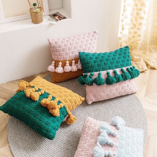 Colorful textured pillows with tassels on a round woven rug.