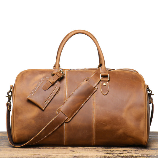 Brown leather duffel bag on a wooden surface with a white background